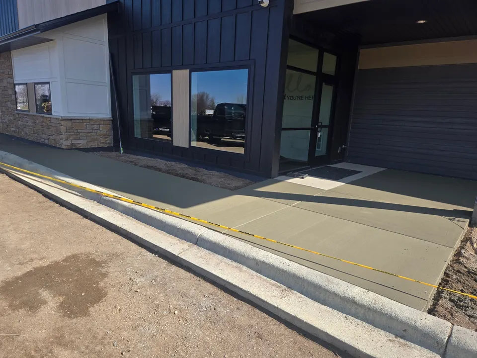 New commercial concrete sidewalk and curb along a storefront entry