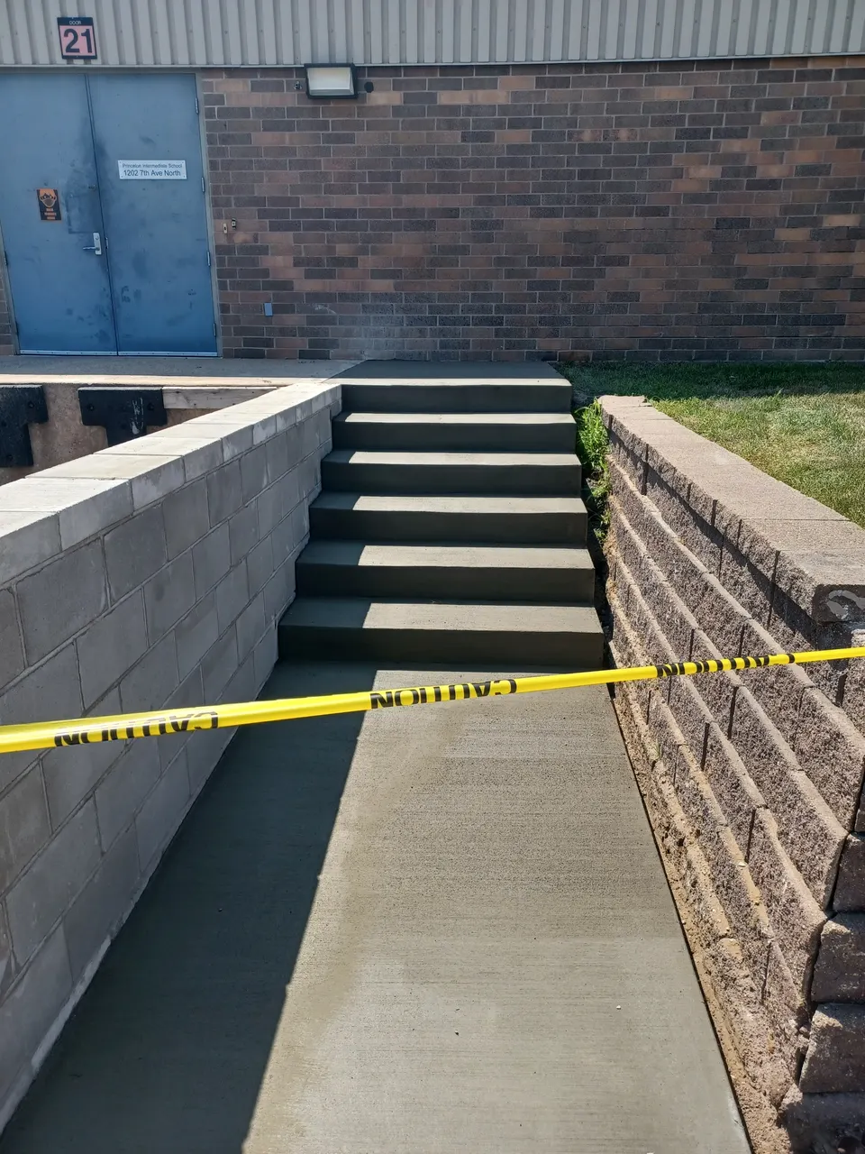 Concrete steps poured between two block retaining walls on a sloped entry
