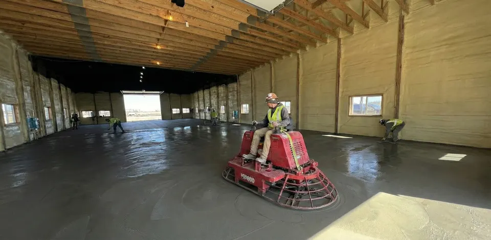 Ride-on power trowel finishing a fresh concrete pole building floor